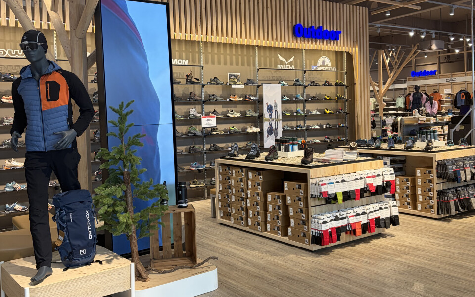 Innenansicht eines Globetrotter Outdoor-Geschäfts mit einer Schaufensterpuppe in Wanderausrüstung, einem digitalen Bildschirm und umfangreichen Schuhdisplays.