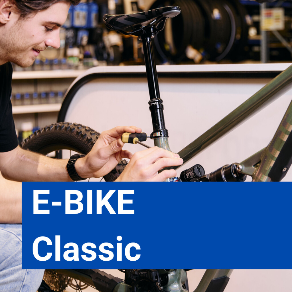 Ein Fahrradmechaniker wartet ein E-Bike in einer Werkstatt und nimmt mit einem Werkzeug Einstellungen vor.