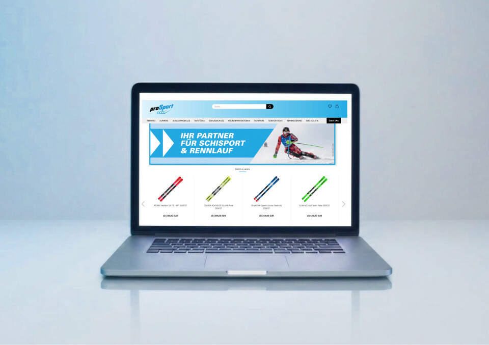 Silver laptop with an e-commerce website for ski equipment on the screen, showing ski poles and a banner for ski sports and racing.