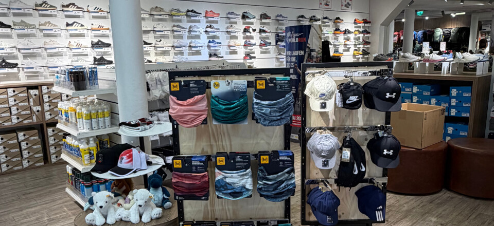 Modernes Sportfachgeschäft-Interieur mit Wänden voller Sneaker und zentralen Auslagen von Sportbekleidung und Accessoires.