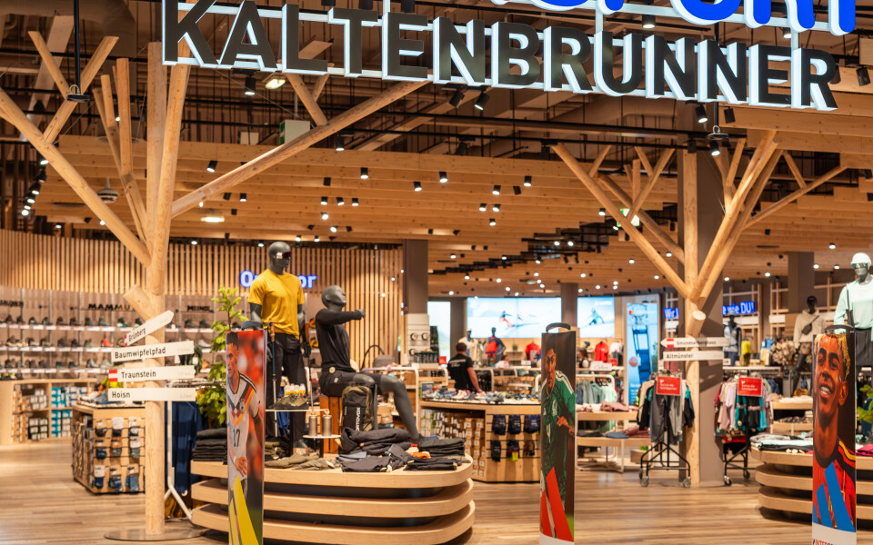 Moderner Intersport Kaltenbrunner Sportfachgeschäftseingang mit Bekleidungs- und Ausrüstungsdisplays.
