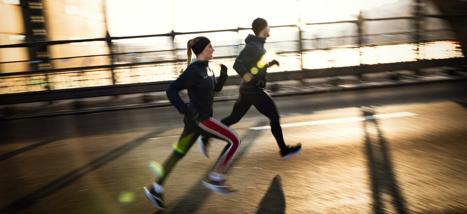 Mann und Frau joggen bei Sonnenaufgang auf einer Brücke, ein aktives Outdoor-Fitnesstraining.