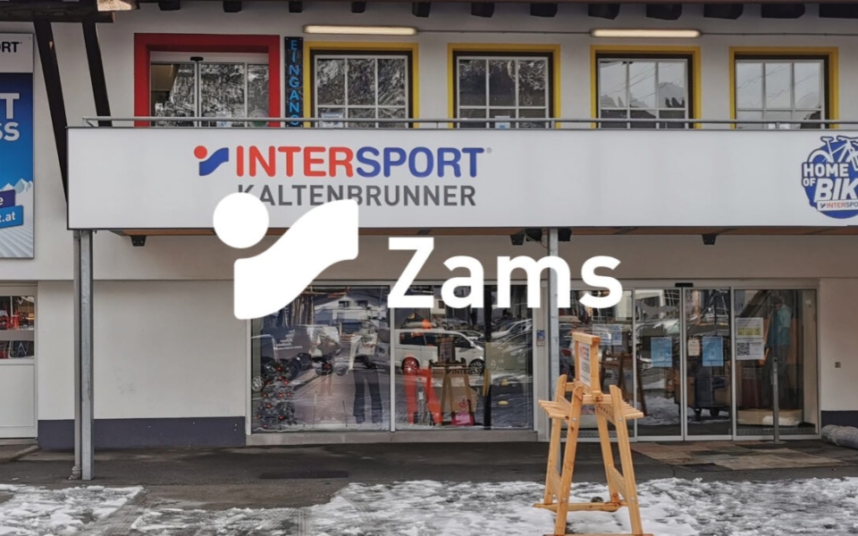 Verschneite Außenansicht des Sport- und Fahrradgeschäfts INTERSPORT Kaltenbrunner in Zams mit einer Holzstaffelei.