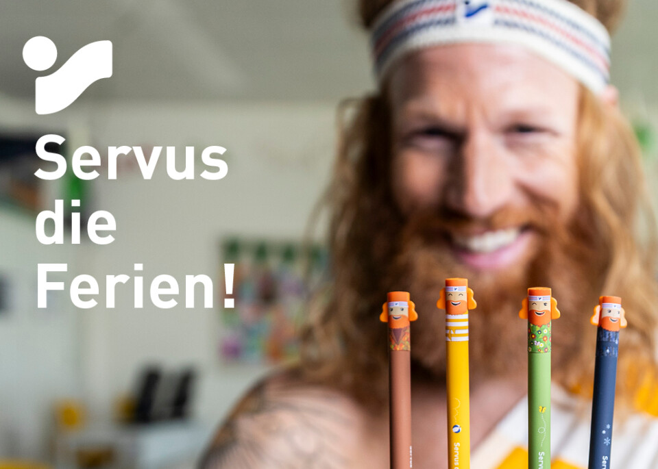 Mann in einem toga-ähnlichen Outfit, der bunte Bleistifte hält und Intersports kostenloses Schulferien-Schreibwarenset bewirbt.